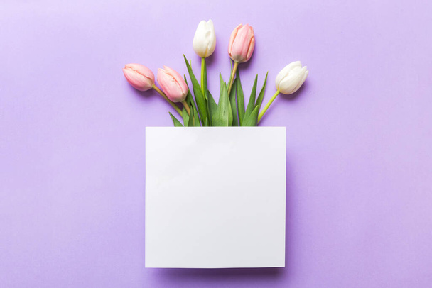 Composition with blank card and beautiful flowers tulip on coloredbackground. top view with space for you desing. - Foto, Imagem