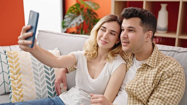 mężczyzna i kobieta para zrobić selfie przez smartfon siedzi na kanapie w domu - Zdjęcie, obraz