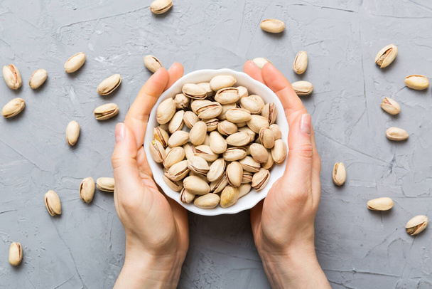 Woman hands holding a wooden bowl with pistachios nuts. Healthy food and snack. Vegetarian snacks of different nuts. - Foto, Bild