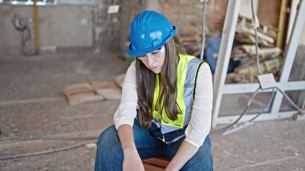 Young beautiful hispanic woman builder sitting tired at construction site - Photo, image