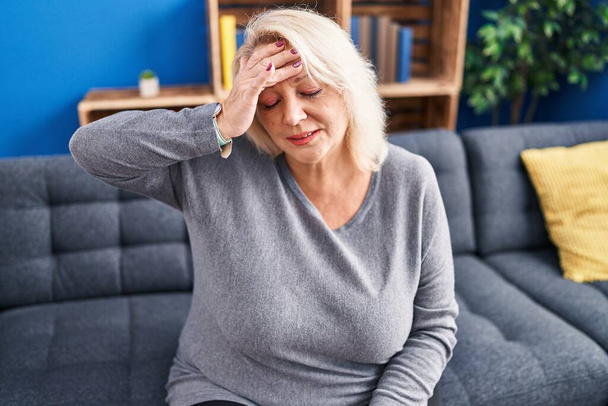 Blonde Frau mittleren Alters leidet zu Hause unter Kopfschmerzen - Foto, Bild