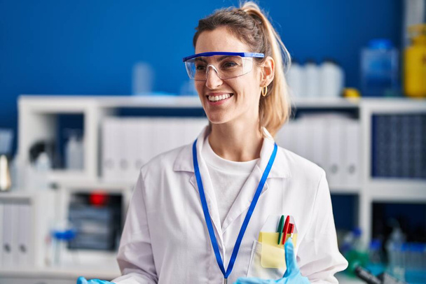 Молода жінка-науковець посміхається впевнено виступає в лабораторії
 - Фото, зображення