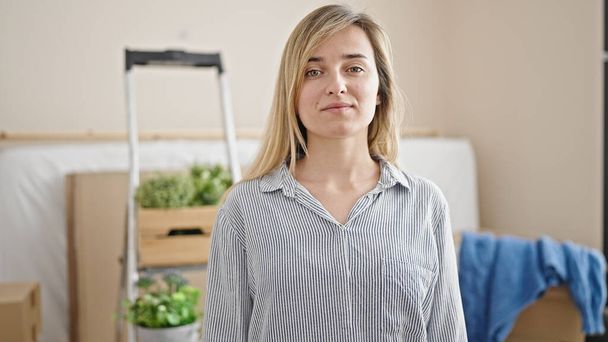 Young blonde woman standing with relaxed expression at new home - Photo, image