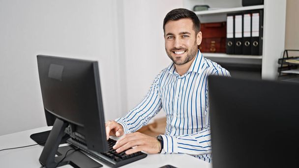 Young hispanic man business worker using computer working at office - 写真・画像