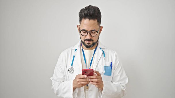 Young latin man doctor using smartphone over isolated white background - Photo, Image