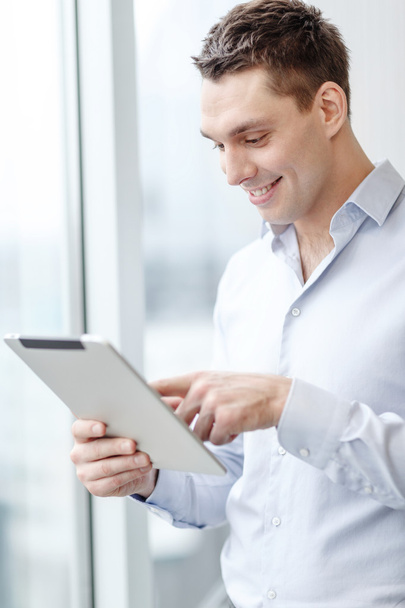 smiling businessman with tablet pc in office - Фото, зображення