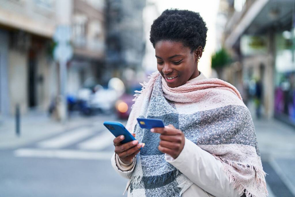African american woman using smartphone and credit card at street - 写真・画像