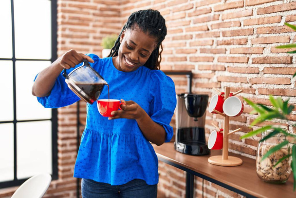 African american woman business worker pouring coffee on cup at home - Fotó, kép