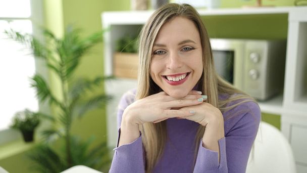 Young blonde woman smiling confident sitting on table at home - Photo, Image
