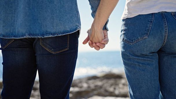 Man and woman couple standing with hands together backwards at seaside - Φωτογραφία, εικόνα