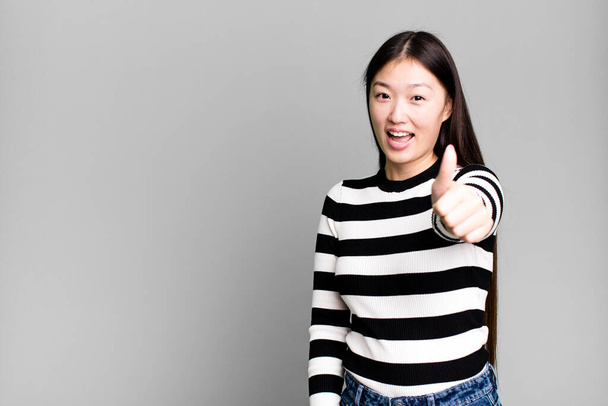 mooie aziatische vrouw gevoel trots, positief glimlachen met duimen omhoog - Foto, afbeelding