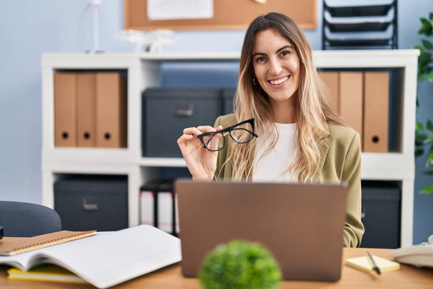 Jonge vrouw zakenman met behulp van laptop met bril op kantoor - Foto, afbeelding