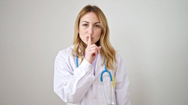 Νεαρή όμορφη Ισπανίδα γιατρός ζητάει ησυχία σε απομονωμένο λευκό φόντο. - Φωτογραφία, εικόνα