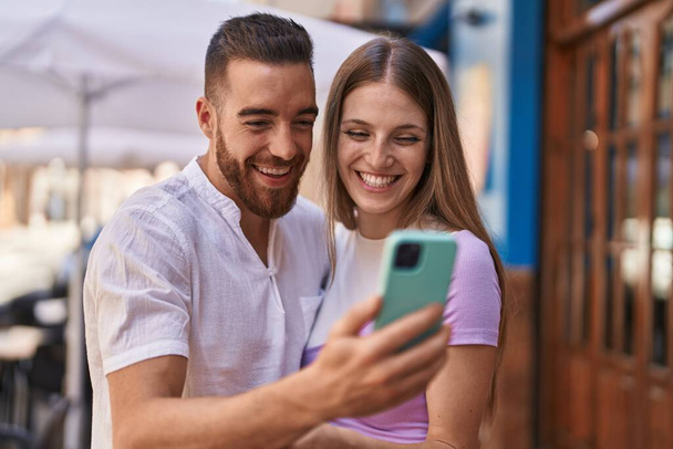 Άνδρας και γυναίκα ζευγάρι χαμογελά αυτοπεποίθηση χρησιμοποιώντας smartphone στο δρόμο - Φωτογραφία, εικόνα
