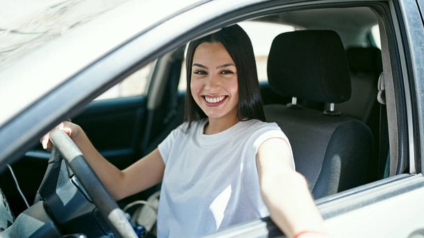 Young beautiful hispanic woman smiling confident driving car at street - Фото, изображение