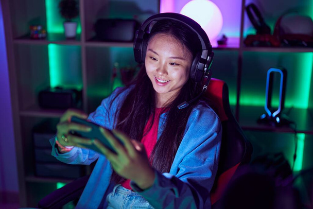 Νεαρή Κινέζα γυναίκα streamer παίζει βιντεοπαιχνίδι χρησιμοποιώντας smartphone στην αίθουσα τυχερών παιχνιδιών - Φωτογραφία, εικόνα