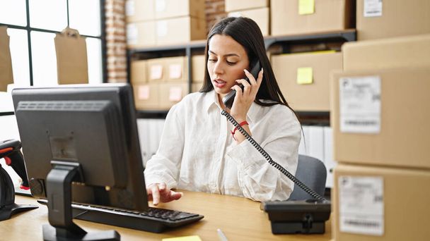 Young beautiful hispanic woman ecommerce business worker using computer talking on telephone at office - Foto, Bild