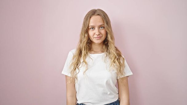 Young blonde woman standing with serious expression over isolated pink background - Фото, изображение