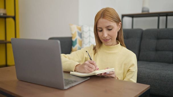 Jeune femme blonde à l'aide d'un ordinateur portable écrit sur ordinateur portable à la maison - Photo, image