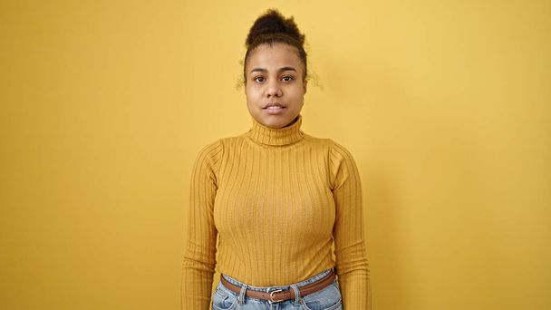 Young african american woman standing with serious expression over isolated yellow background - Foto, immagini