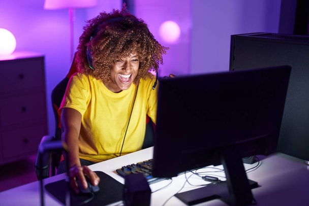 Африканская американка стример, играющая в видеоигры с помощью компьютера в игровой комнате - Фото, изображение