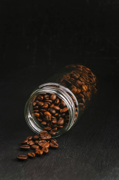 Fragrant morning coffee. Favorite checks. Spiced coffee. Coffee consumers are scattered over a dark wooden background. Coffee cup and beans on a black background with copy space,  banner for a menu - Photo, Image
