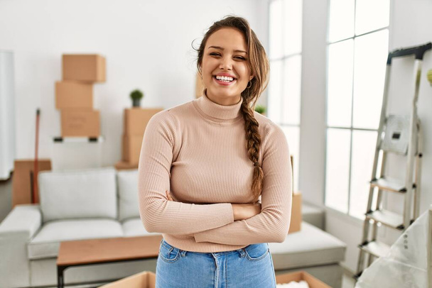 Young beautiful hispanic woman smiling confident standing with arms crossed gesture at new home - Photo, image