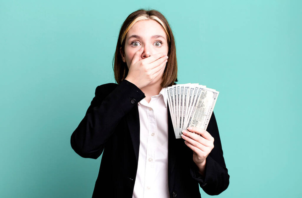 young pretty woman covering mouth with hands with a shocked. dollar banknotes - Фото, зображення