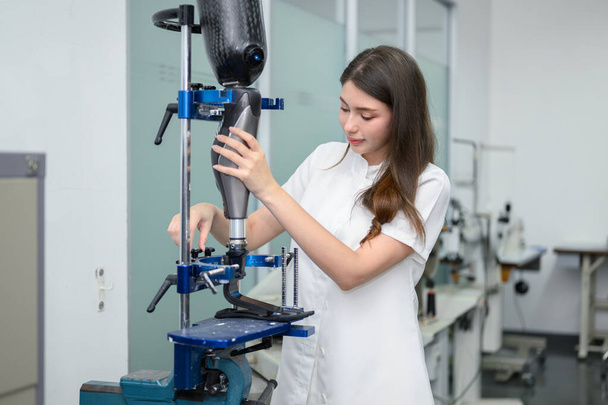 Protez bacak kontrolü yapan ve laboratuvarda çalışan genç bayan teknisyen, protez üretiminde yüksek teknoloji uzmanı, engelliler için yeni yapay uzuv üretimi - Fotoğraf, Görsel
