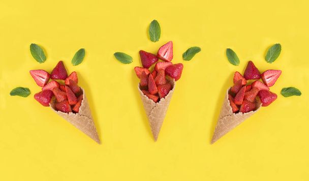 Ice cream cone with strawberry on the yellow background. Top view. Close-up. - Photo, Image