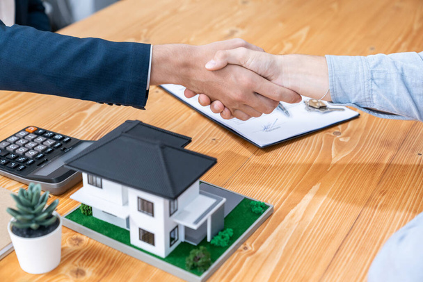 Finalizing house loan agreement with handshake, buyer and real estate agent celebrate accomplishment of property ownership with sense of satisfaction. New home owner shake hand with broker. Entity - Photo, Image