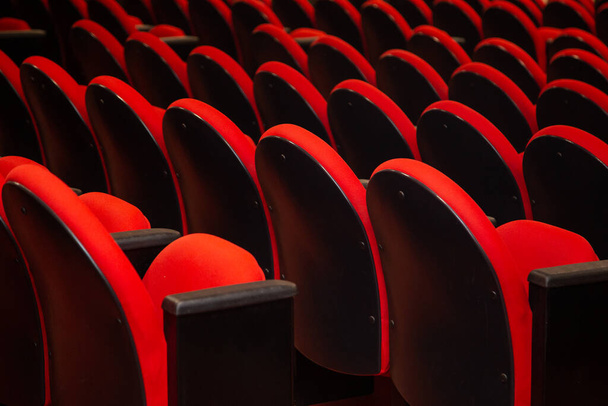 Detalhe de algumas fileiras de poltronas vermelhas em um teatro que está vazio. - Foto, Imagem
