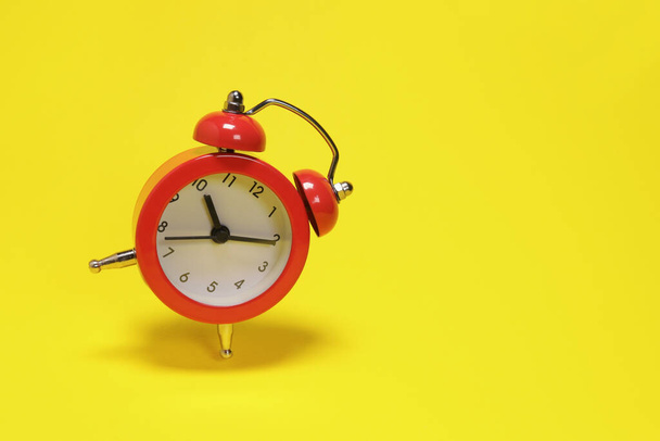Reloj despertador rojo volador sobre fondo amarillo. espacio de copia para texto - Foto, imagen