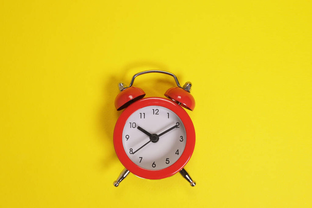 red alarm clock on yellow background - Foto, afbeelding