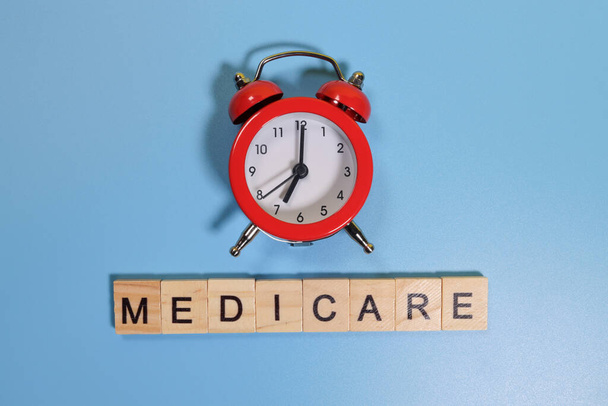 Palabra de Medicare y reloj despertador sobre fondo azul - Foto, imagen