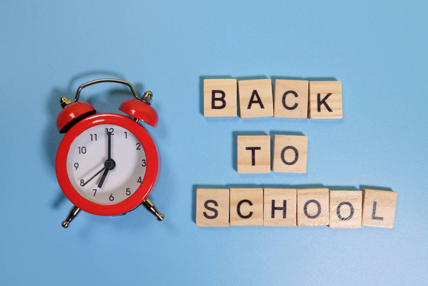 Okula geri dön mavi arkaplan üzerindeki yazıt ve alarm saati - Fotoğraf, Görsel