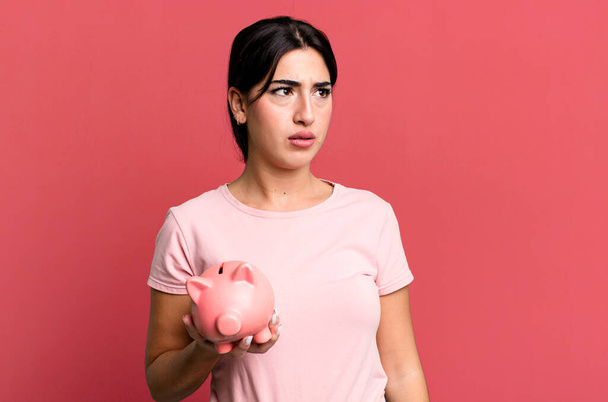 feeling sad, upset or angry and looking to the side. with a piggy bank - Foto, Imagem