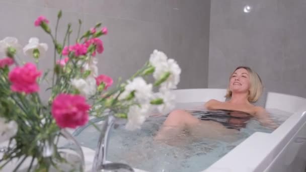 Jeune femme en maillot de bain relaxant assis dans un bain à remous dans un spa de luxe. Femme heureuse dans le bain, hydrothérapie relaxante dans le centre de beauté. - Séquence, vidéo