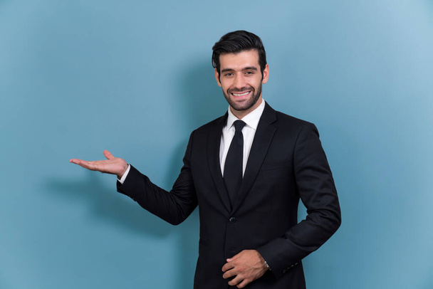 Уверенный бизнесмен в формальном костюме делает жест за руку, чтобы показать продвижение или рекламу на пустом пространстве с возбужденным выражением лица и жестом на изолированном фоне. Пылкий - Фото, изображение