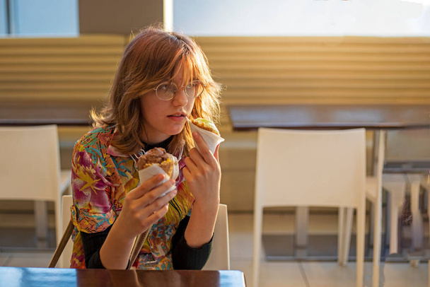 стильная девушка-подросток, держащая два мороженых в кафе в солнечный день. Повседневный стиль жизни - Фото, изображение