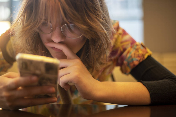 Tyttö tenager lukee älypuhelimella. Verkko-oppiminen takaisin kouluun - Valokuva, kuva