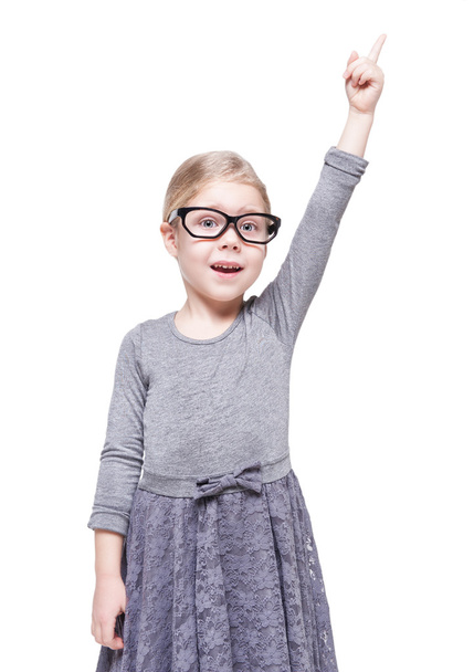 Beautiful little girl in glasses showing on something by finger - Фото, изображение