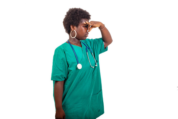 un beau jeune médecin stagiaire avec afro debout sur fond blanc sentant quelque chose puant. - Photo, image