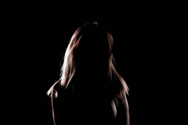 silhouette contour of a beautiful blond girl. Side lit studio portrait on dark background. - Photo, image