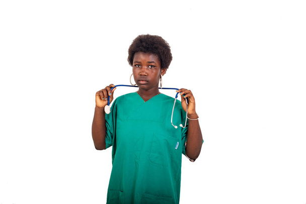 eine schöne junge internistische Ärztin mit Afro steht auf weißem Hintergrund und hält Stethoskop am Hals, während sie in die Kamera schaut. - Foto, Bild