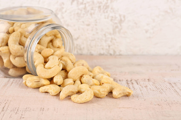 Jar with tasty cashew nuts on light background - Φωτογραφία, εικόνα