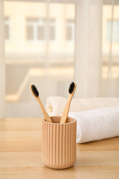 Houder met bamboe tandenborstels op tafel in de kamer, close-up - Foto, afbeelding