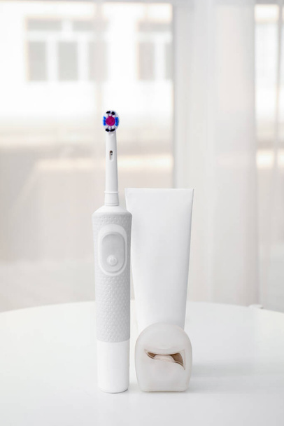Electric toothbrush with paste on table in room - Фото, изображение