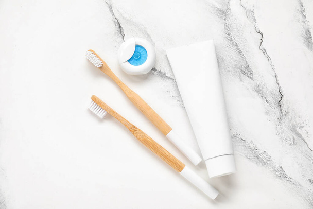 Hilo dental, pasta y cepillo de dientes de bambú sobre fondo de mármol blanco - Foto, Imagen