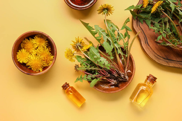 Kozmetikai olajos palackok és pitypang virágos tálak sárga alapon - Fotó, kép